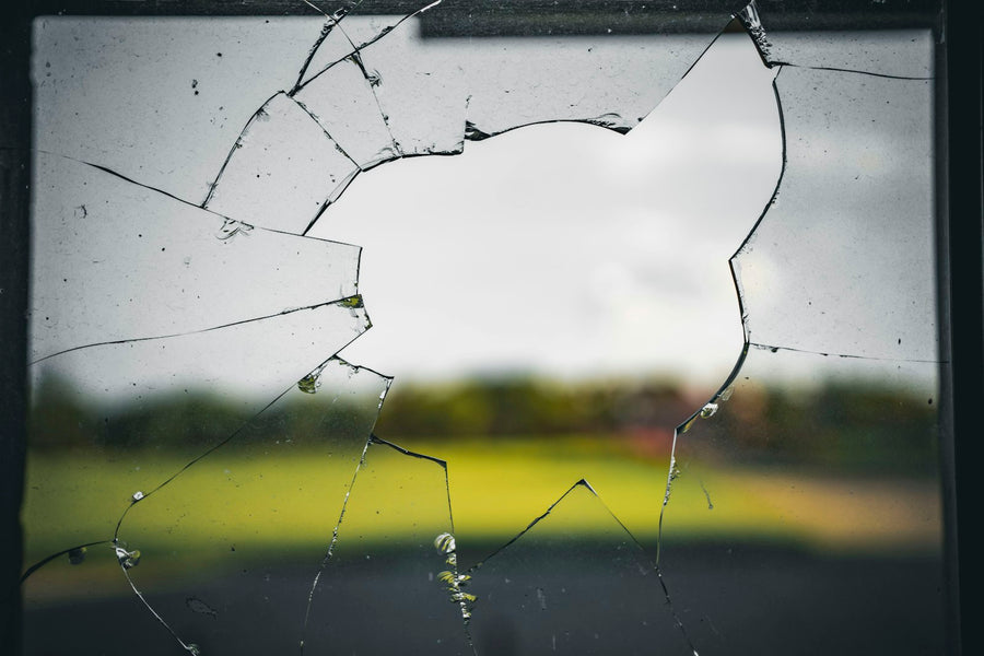 A broken glass window pane with a field visible through it