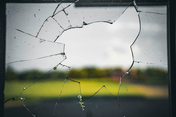 A broken glass window pane with a field visible through it