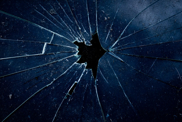 A pane of glass with a central impact hole and cracks radiating outward
