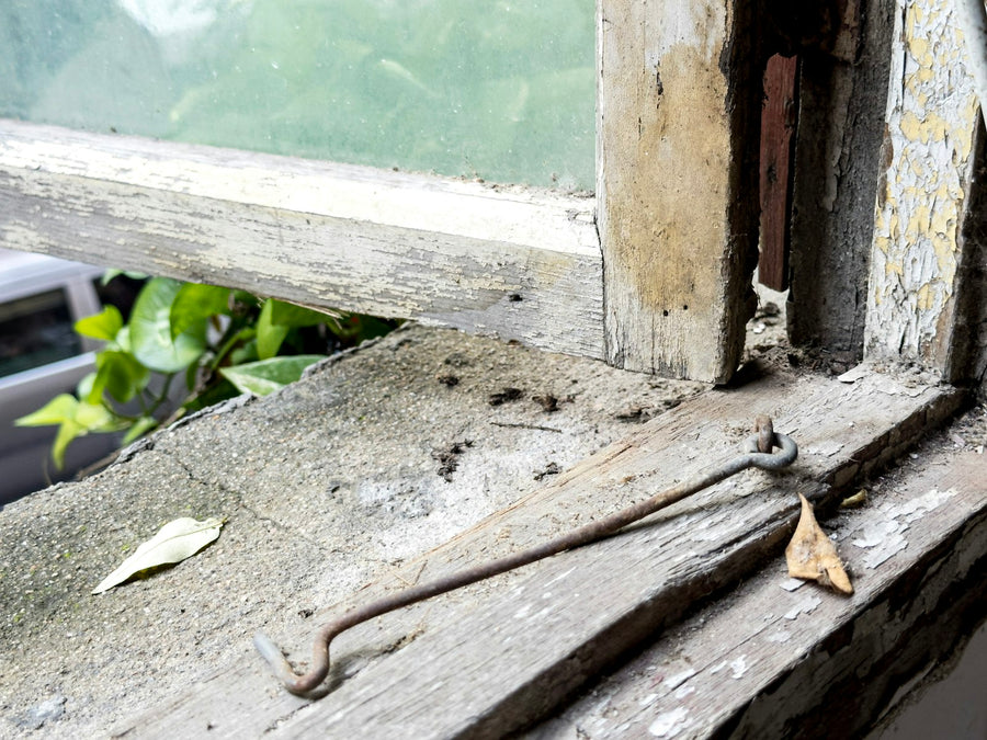 Close-up of an old weathered window latch on a painted frame
