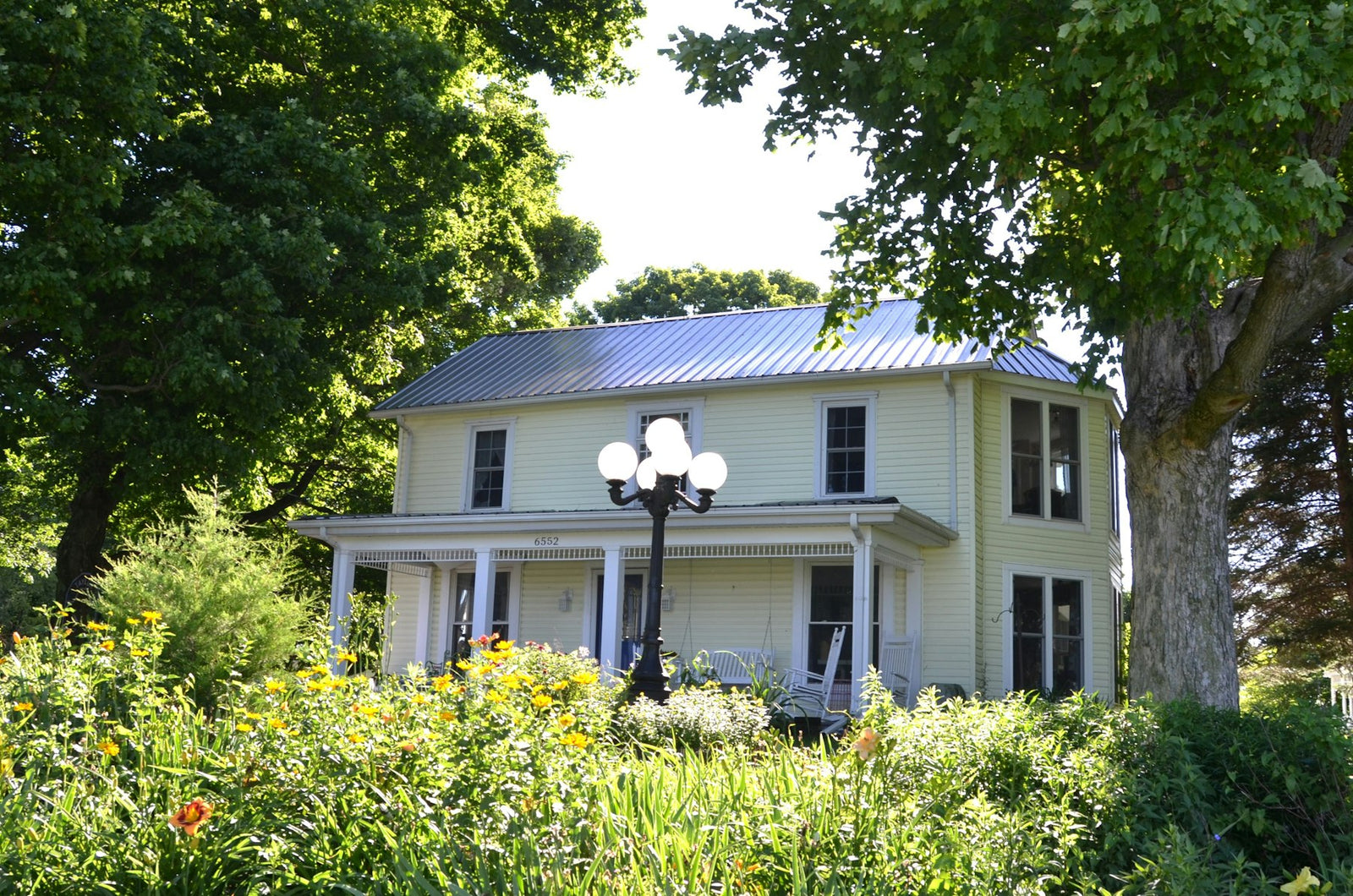 Historic house with a glowing porch lamp amid green foliage