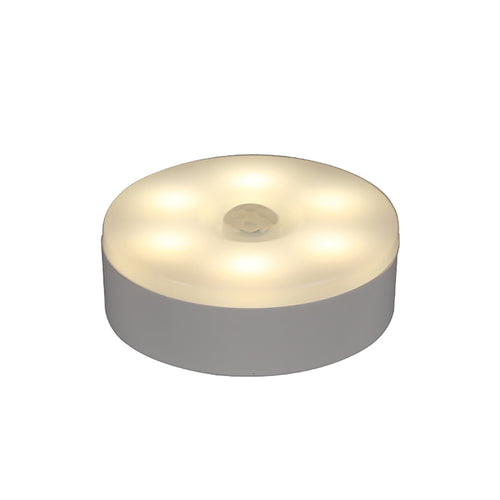 Round white stick-on motion sensor night light, lit warm, with the motion sensor dome in the center