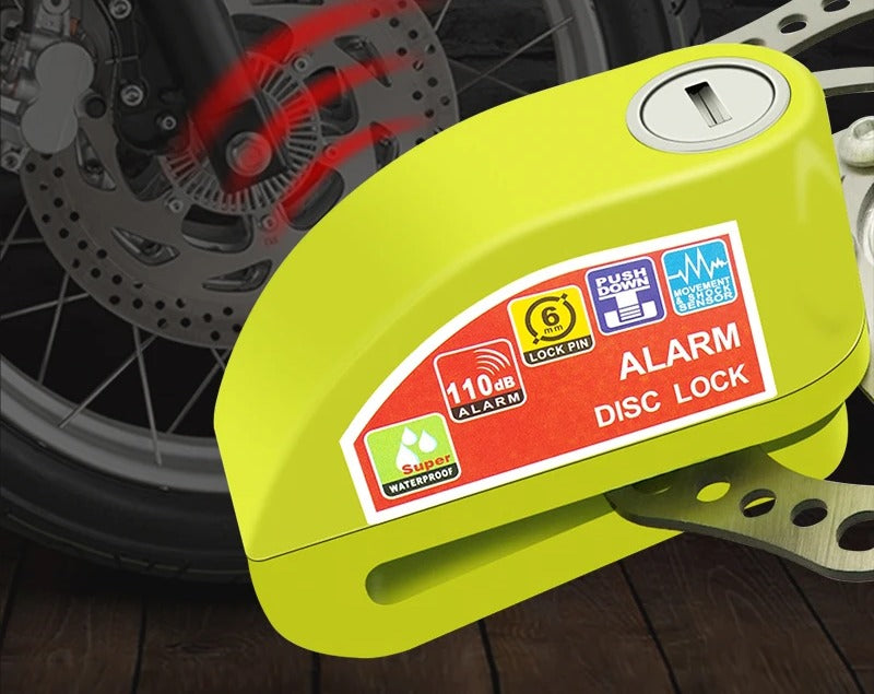 Yellow disc lock alarm clamped on a motorcycle brake disc in front of a spoked wheel