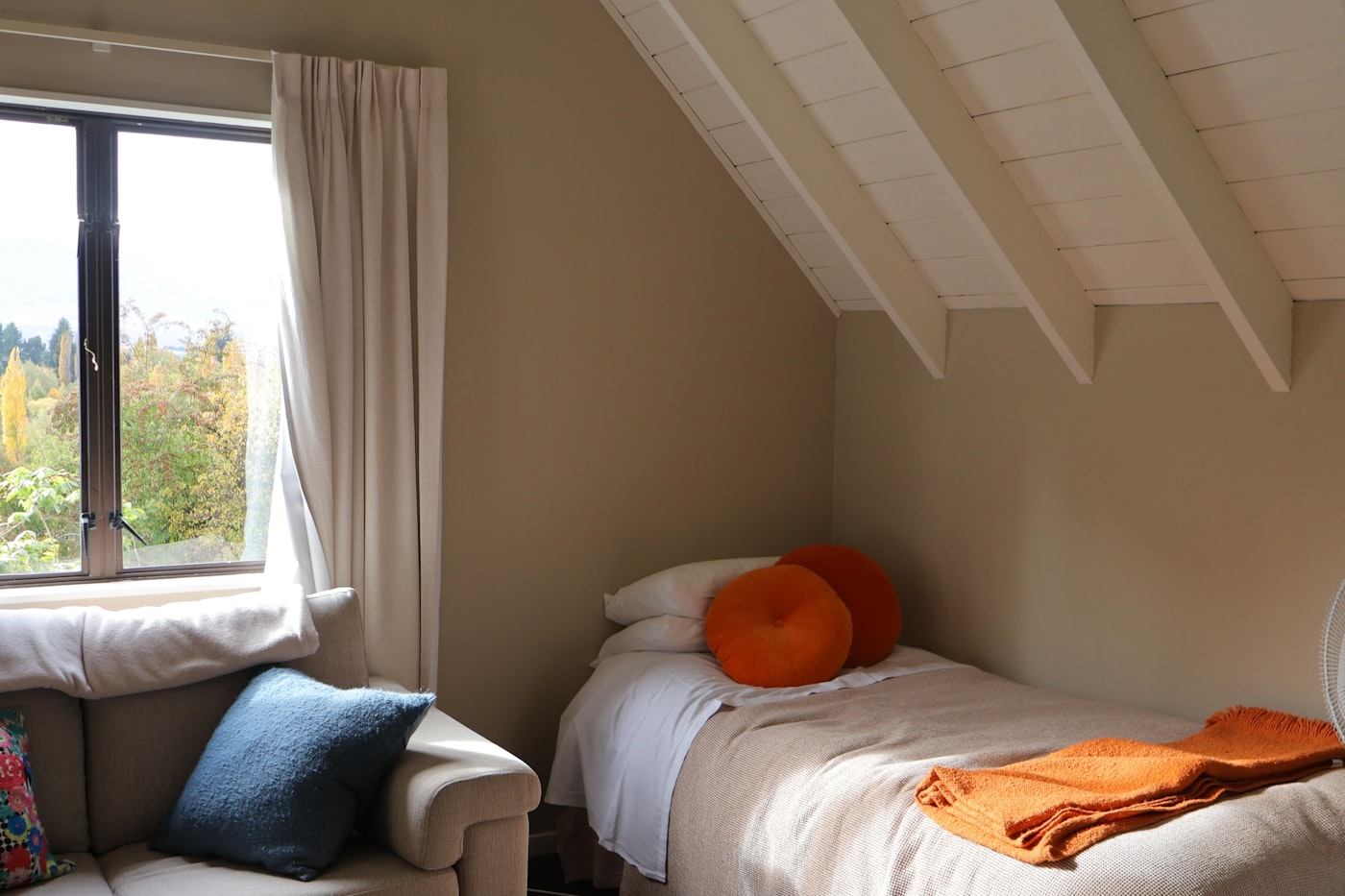 Tidy dorm-style single bedroom with a bed, armchair, and bright window