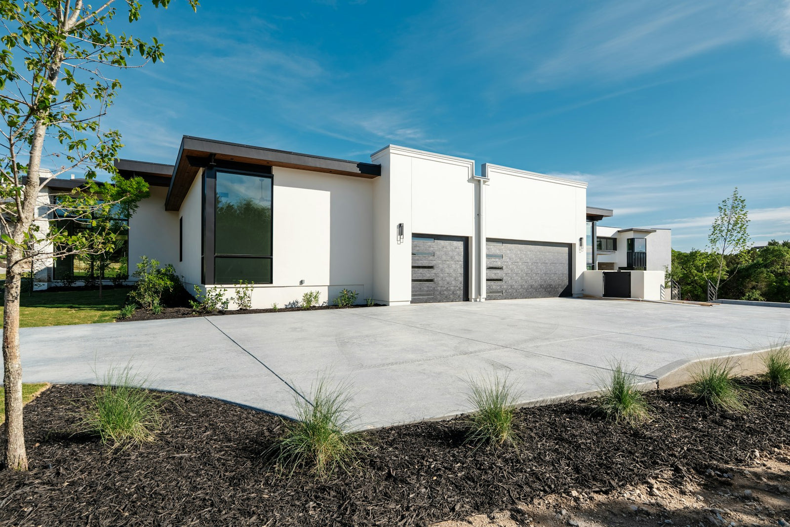 Modern white house with two garage doors and a concrete driveway