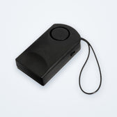 Black door knob touch alarm with its cord loop, on a soft grey background