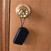 Door knob touch alarm hanging by its cord from a brass round knob on a wooden door