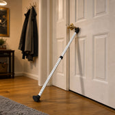 White adjustable door security bar braced from the floor up under the handle of a closed white front door