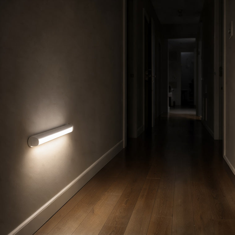 LED motion sensor light bar lit low on a hallway wall at night, lighting the wooden floor
