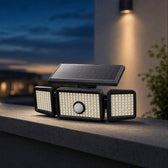 TremShield solar motion security light, a single unit with three adjustable LED heads lit at dusk on an outdoor wall
