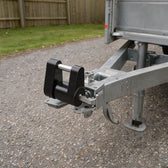 Black keyed coupler lock fitted on the ball-hitch coupler of a galvanized utility trailer on a gravel driveway